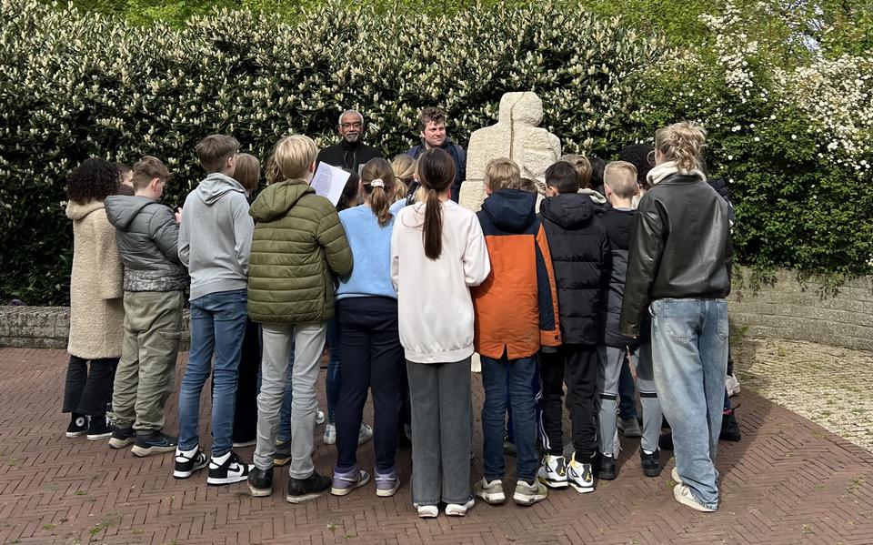 Kinderen uit groep 7 van IKC Warande bij het herdenkingsmonument in het Stadspark. Daarachter Tony Merkelbach (links) en leerkracht Gijs van Asselt.